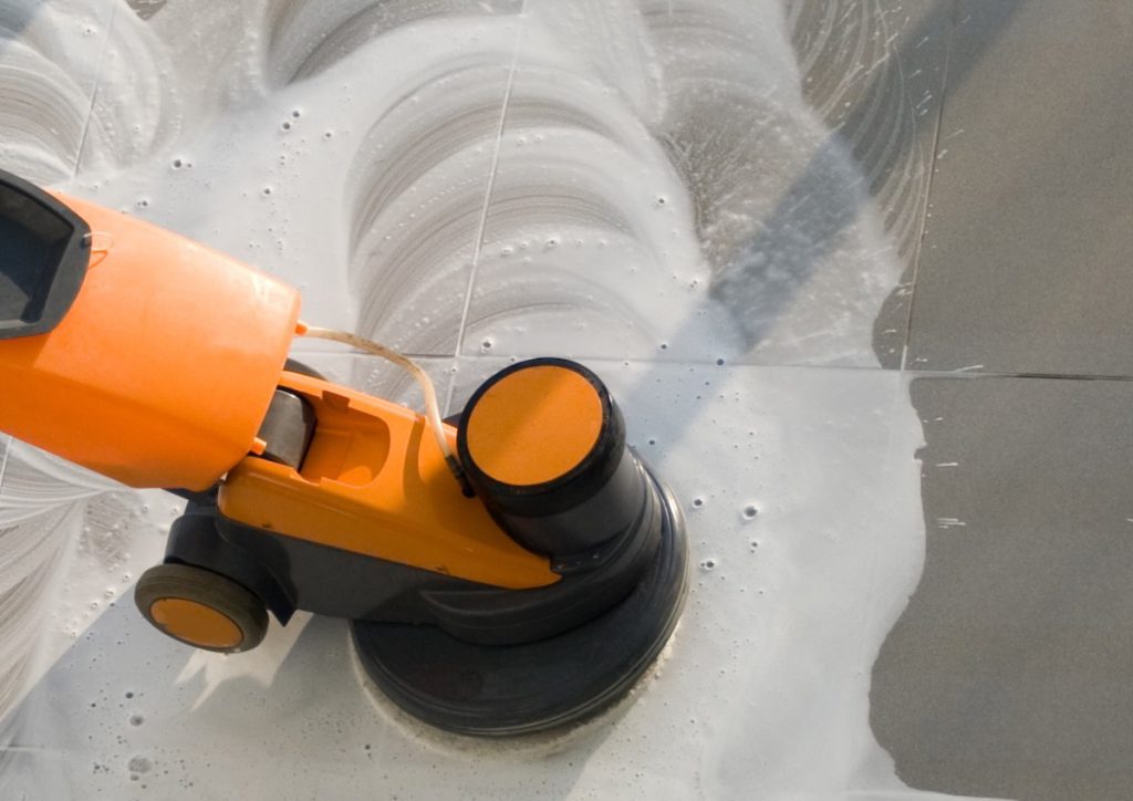 Orange floor scrubber head working through foam