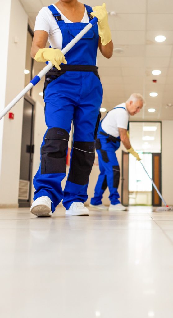 Two cleaners mopping a bright corridor