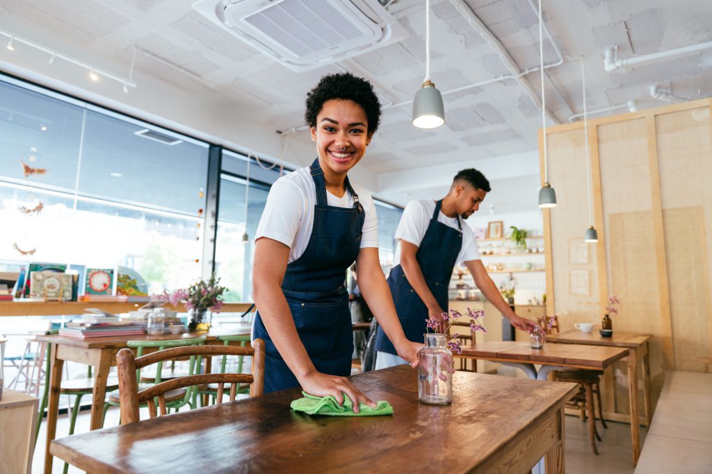 Cleaners wiping tables in a cafe-style breakout area
