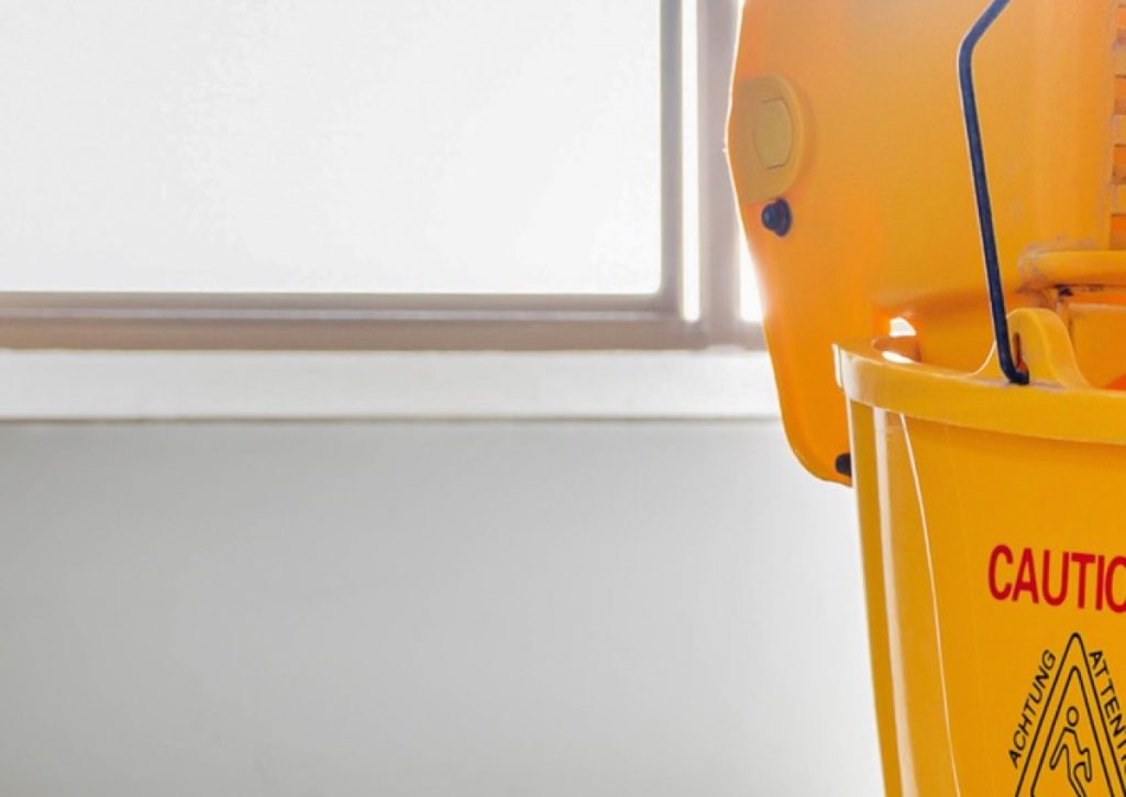 Yellow mop bucket against a wall