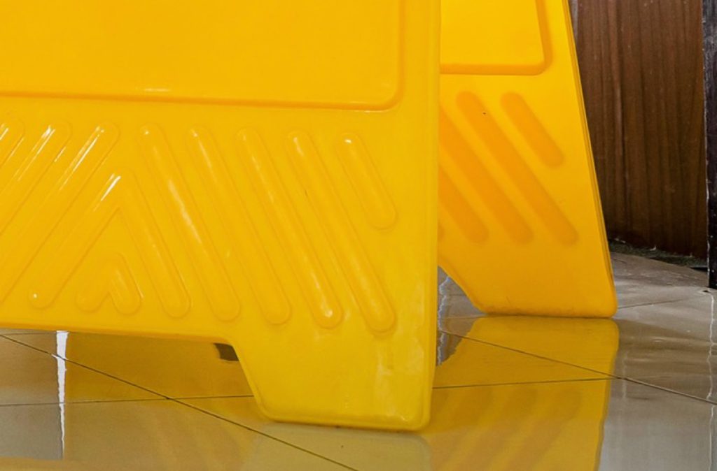 Yellow caution sign on a wet tiled floor