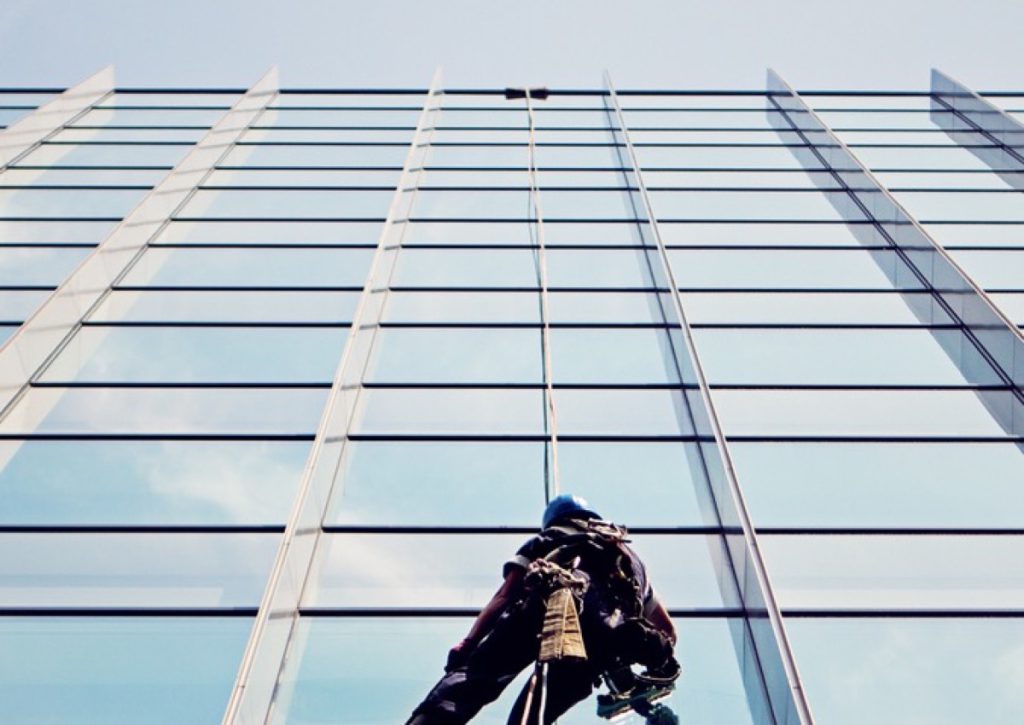 Window cleaner abseiling down a glass tower