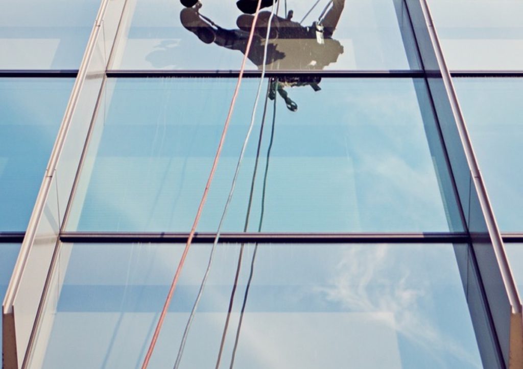 Window cleaner on ropes against the glazing