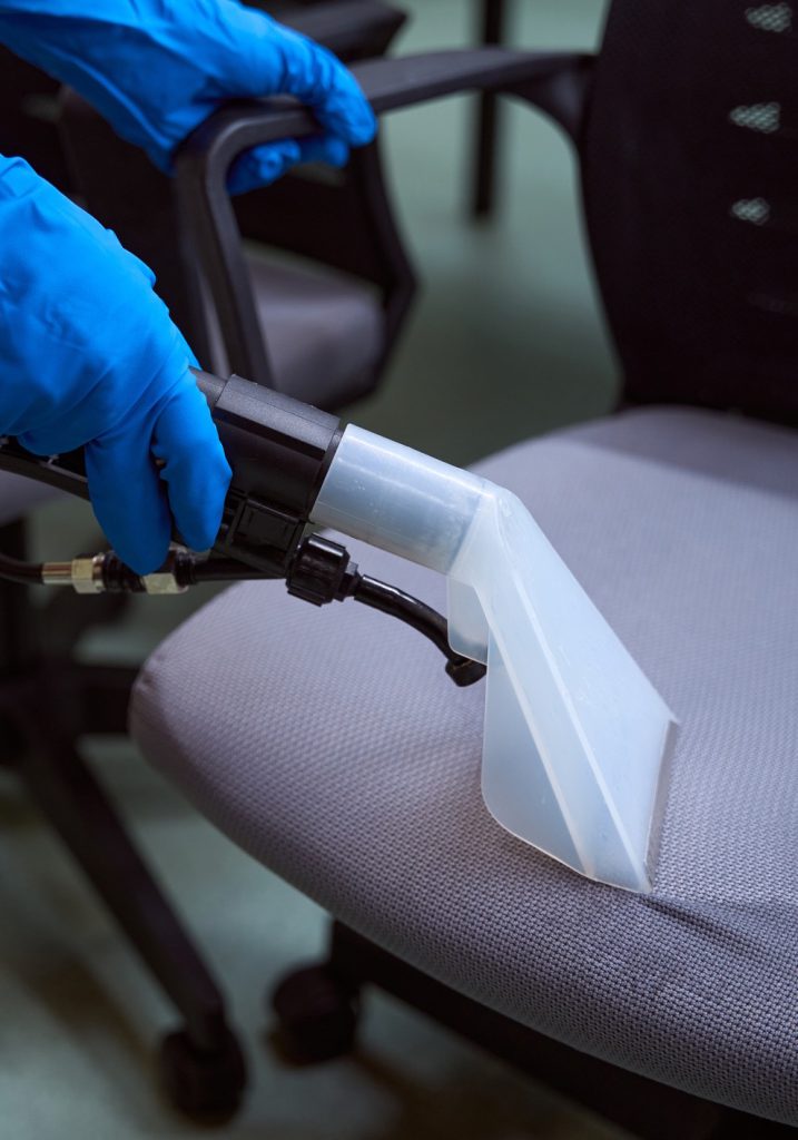 Gloved hand spraying the seat of an office chair