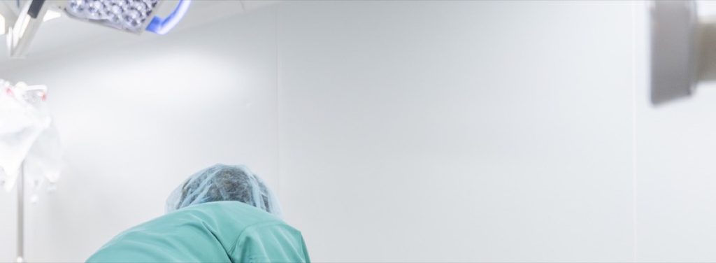 Cleaner in scrubs bending over a theatre table