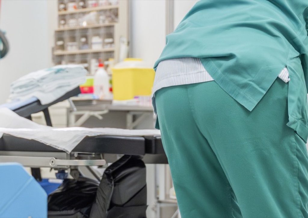 Cleaner in green scrubs beside a theatre table