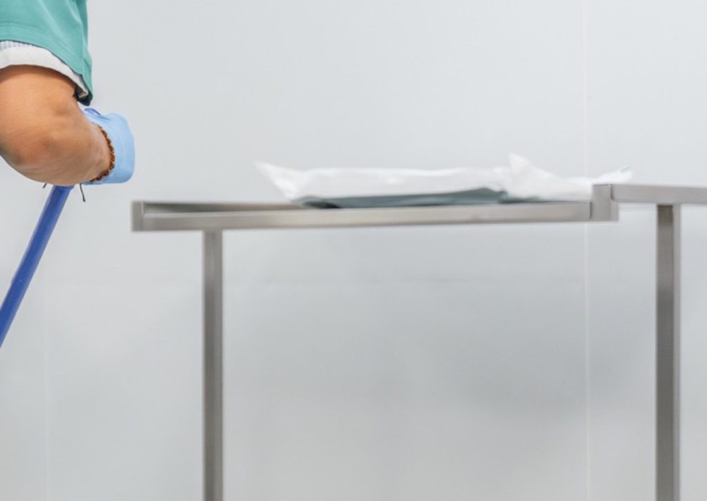Gloved hand at a stainless steel instrument table