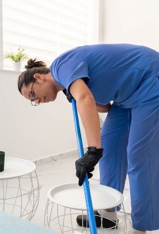 Cleaner in blue scrubs wringing a mop into a bucket
