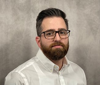 Studio headshot of Joseph Vani, dark beard and glasses, in a white shirt
