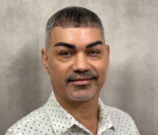 Studio headshot of Samuel Perez, short greying hair, in a patterned white shirt